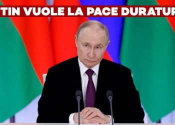 Vladimir Putin alla scrivania con bandiere sullo sfondo