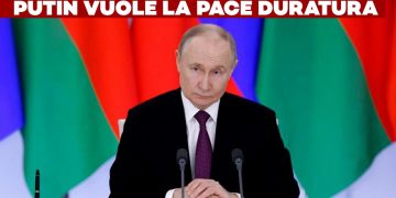 Vladimir Putin alla scrivania con bandiere sullo sfondo