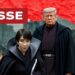 Città crepuscolare. Sanae Takaichi, Donal Trump e Friedrich Merz vestiti con mantelli scuri in primo piano