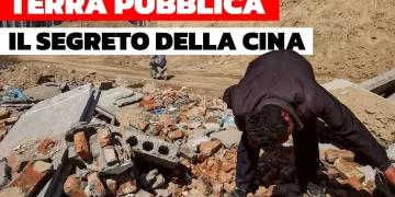 Un uomo rovista fra le macerie di un cantiere. Sullo sfondo, un altro uomo passa in motorino su una strada sterrata del cantiere