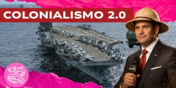 Una portaerei. Marco Rubio con un cappello da colono e un microfono in mano in primo piano