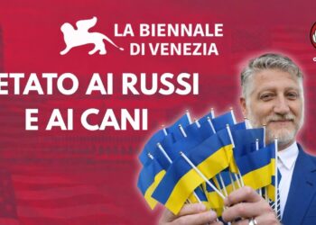 Venezia sullo sfondo. Alessandro Giuli con un po' di bandierine ucraine fra le mani in primo piano