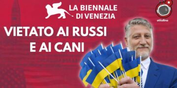 Venezia sullo sfondo. Alessandro Giuli con un po' di bandierine ucraine fra le mani in primo piano